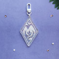 A clear acrylic keychain charm with a silver clasp, featuring a white dragon design, displayed on a textured purple background with small decorative star and leaf props.