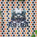 A die-cut sticker featuring a stylized, colorful monster cat illustration, placed on a white background with a repeating pattern of orange, black, and beige polka dots, with small green leaves in the corners.