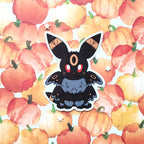 A die-cut sticker of a black moth fox with glowing red eyes and orange markings, displayed on a watercolor background of orange and yellow pumpkins.