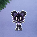 A die-cut sticker featuring a cute chibi panda character in a dark purple hooded outfit, displayed on a textured lavender background with a green leaf in the top-left corner.