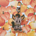 A cute acrylic keychain charm featuring a stylized cartoon fox character with a silver lobster clasp, set against a watercolor pumpkin patterned background.