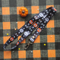 A Halloween-themed lanyard with a black background and cute balls. It features a silver metal lobster clasp at one end.