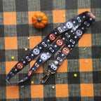 A Halloween-themed lanyard with a black background and cute balls. It features a silver metal lobster clasp at one end.