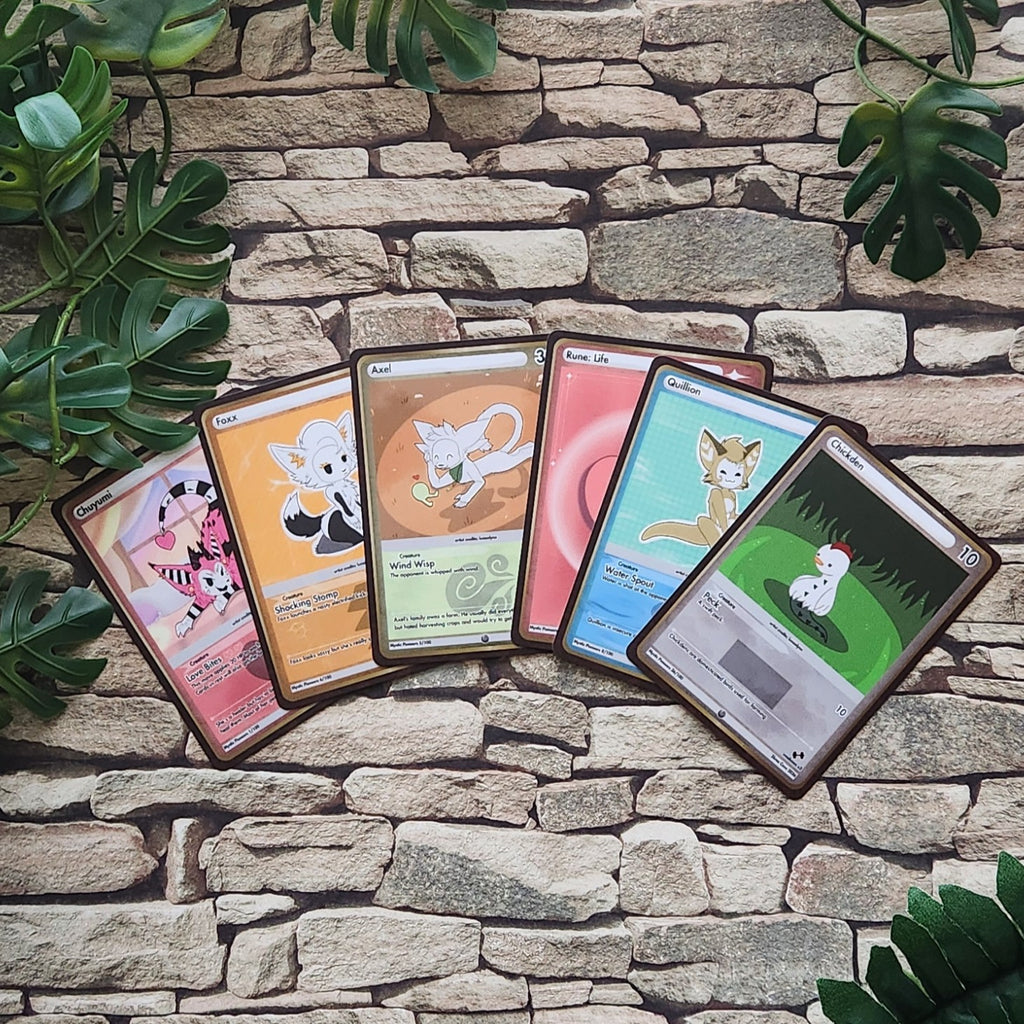 Five illustrated trading cards fanned out on a stone wall background with green leaves around the edges. The cards feature different fantasy animal designs and pastel-to-real color schemes.